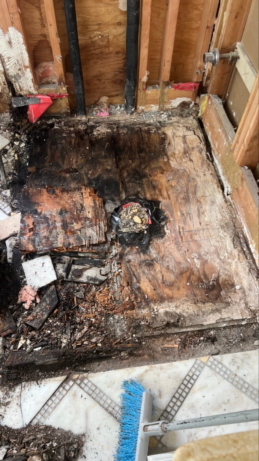 Rotted, mold-stained subfloor exposed under the master bathroom shower of a Darien, CT home before remediation