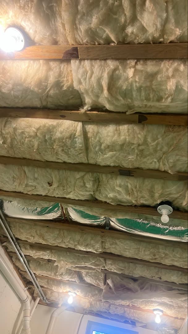 Stained fiberglass batt insulation in the exposed ceiling joists over a basement laundry room in New Canaan, CT