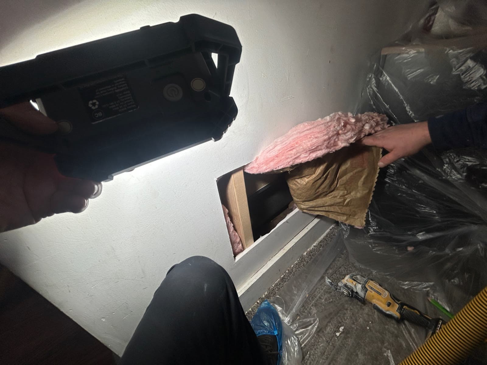 Exploratory opening cut into a wall behind a Shelton, CT bathroom showing insulation in the cavity