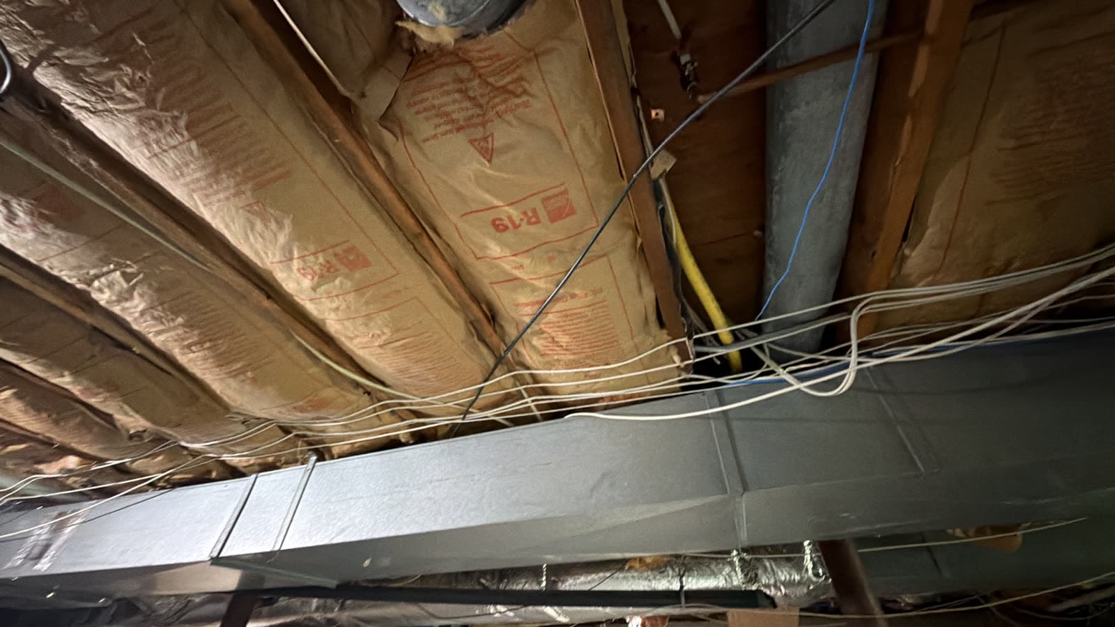 Sagging kraft faced fiberglass batt insulation falling out of the floor joist bays under a Weston, CT home