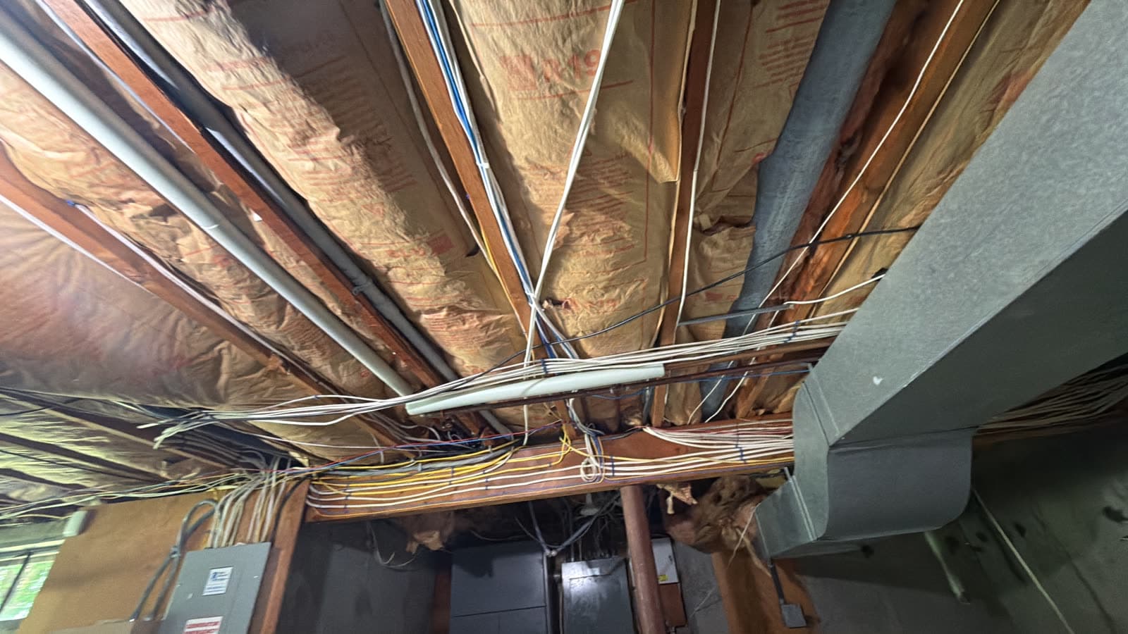 Sagging kraft faced fiberglass batt insulation falling out of the floor joist bays under a Weston, CT home