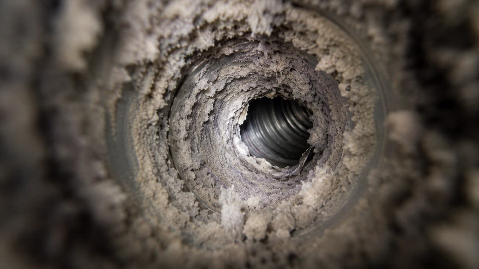 Flexible dryer duct packed with thick lint buildup, a real fire hazard, before air duct cleaning in a Connecticut home