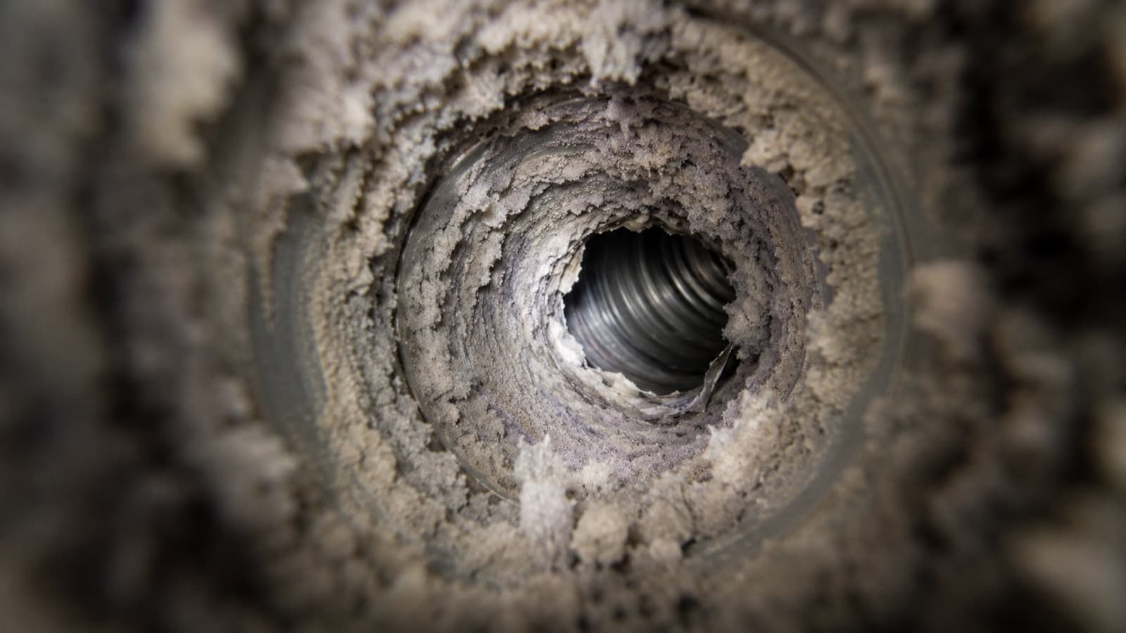 Flexible dryer duct packed with thick lint buildup, a real fire hazard, before air duct cleaning in a Connecticut home