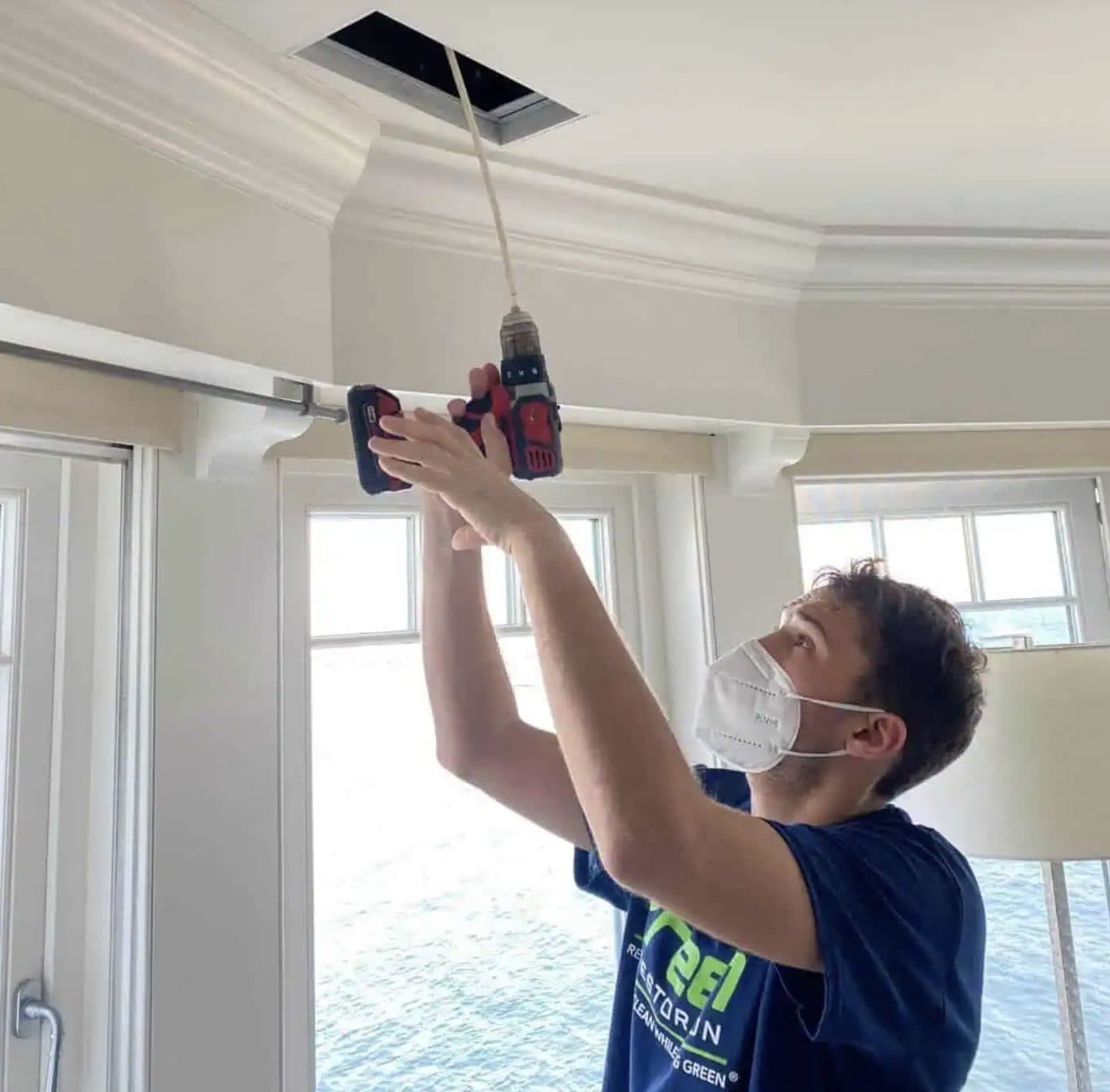 Green Restoration technician removing a ceiling supply register to access and clean the duct system in a Connecticut home