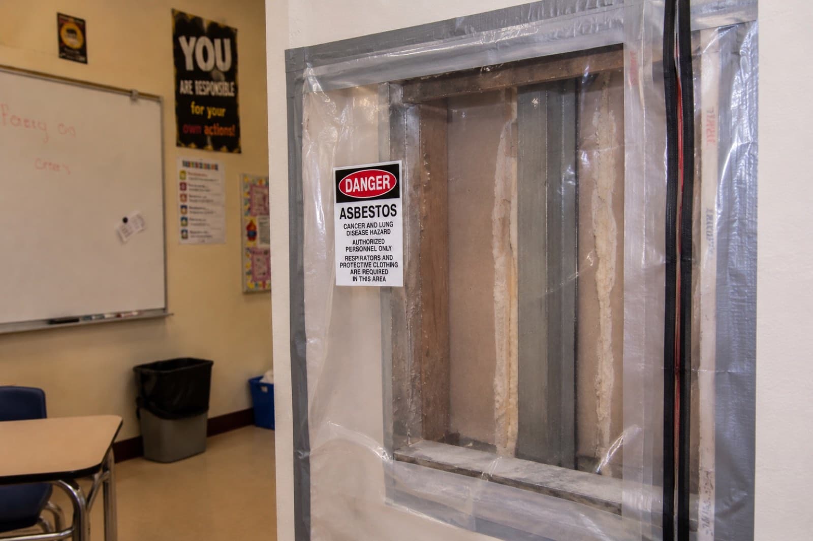 Sealed poly containment with a danger asbestos warning sign during a licensed abatement project