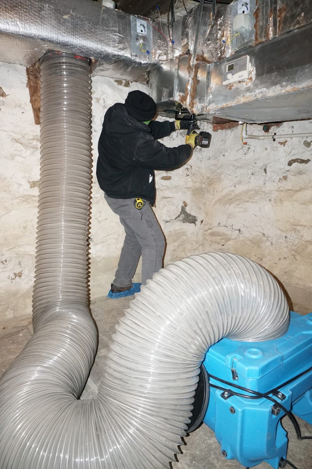 Deteriorating friable asbestos pipe insulation wrapped around a basement steam line, showing crumbling white TSI lagging with loose fibers exposed at the joints in a pre 1985 residential boiler room