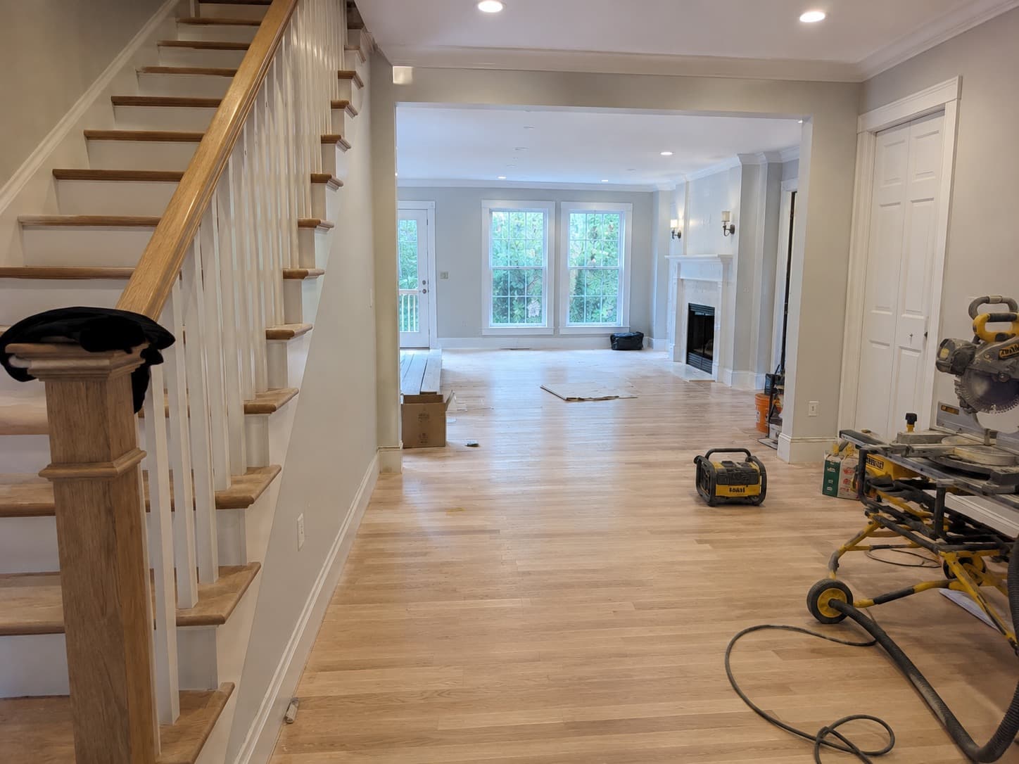 Connecticut home interior mid-reconstruction with new white oak flooring, refinished staircase, and trim work after water damage mitigation