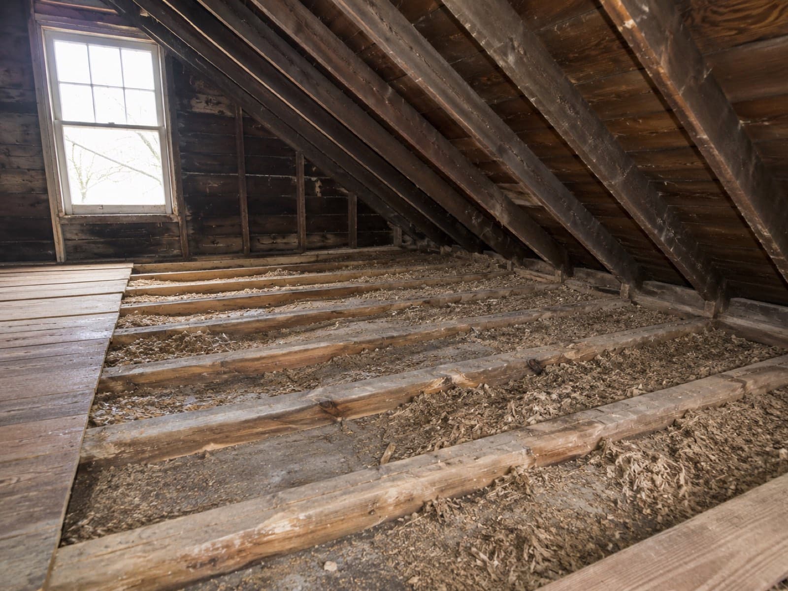 Old degraded and fallen insulation between crawl-space joists before removal and replacement
