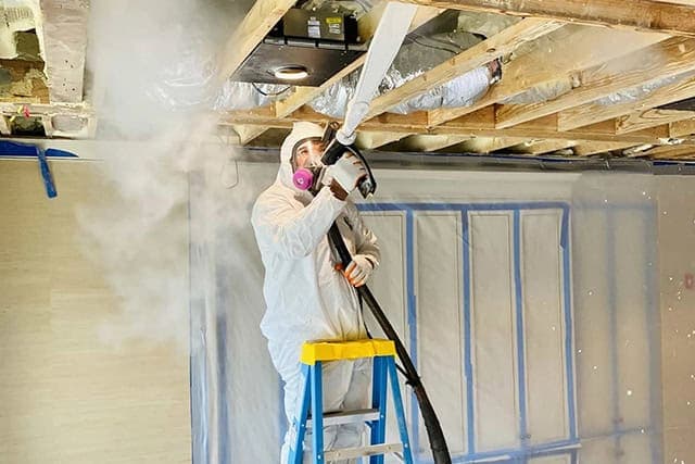 CO2 dry ice pellets blasting black mold growth off an attic rafter framing member, a plume of cold vapor visible at the nozzle tip, documented during a Green Restoration dry-ice attic scope in the tri-state