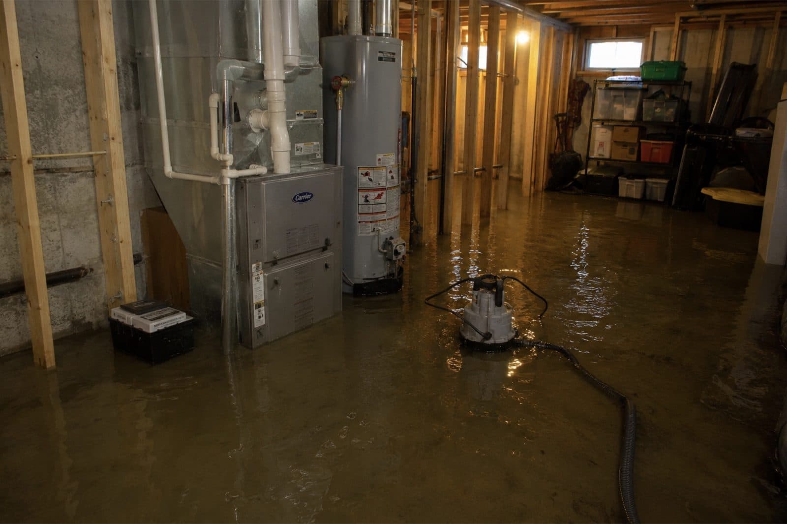 Flooded basement with standing water around the furnace and water heater in a Newtown Connecticut home during emergency water extraction