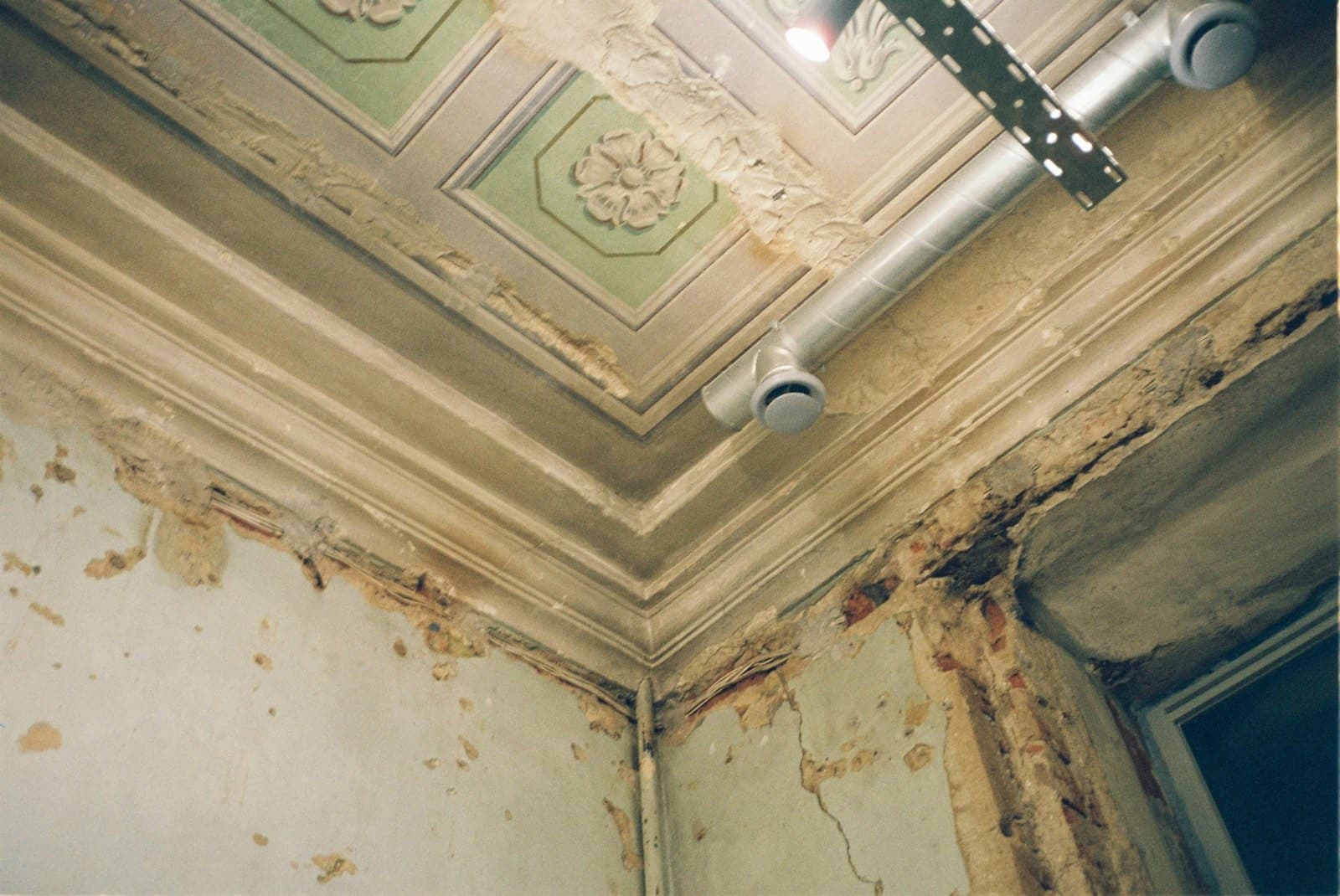 Water-damaged interior ceiling with peeling plaster and exposed lath caused by an active roof leak, documented during a Green Restoration interior inspection in the tri-state