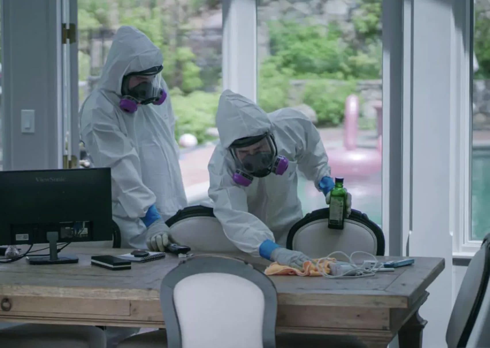 Two Green Restoration technicians in full Tyvek suits, full-face respirators, and nitrile gloves decontaminating surfaces during a Category 3 biohazard cleanup in a Connecticut home