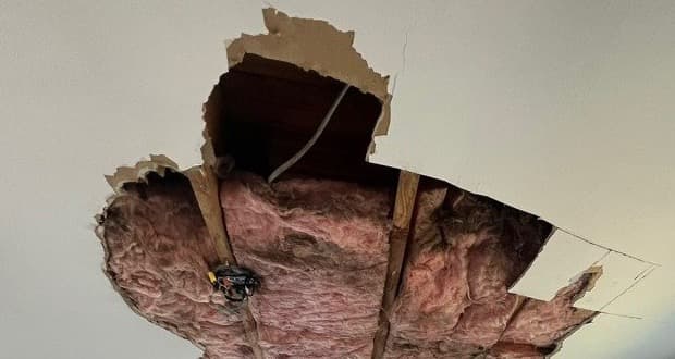 Bedroom ceiling collapse with saturated insulation hanging through broken drywall after a hidden leak in a Yonkers New York area home, documented by Green Restoration